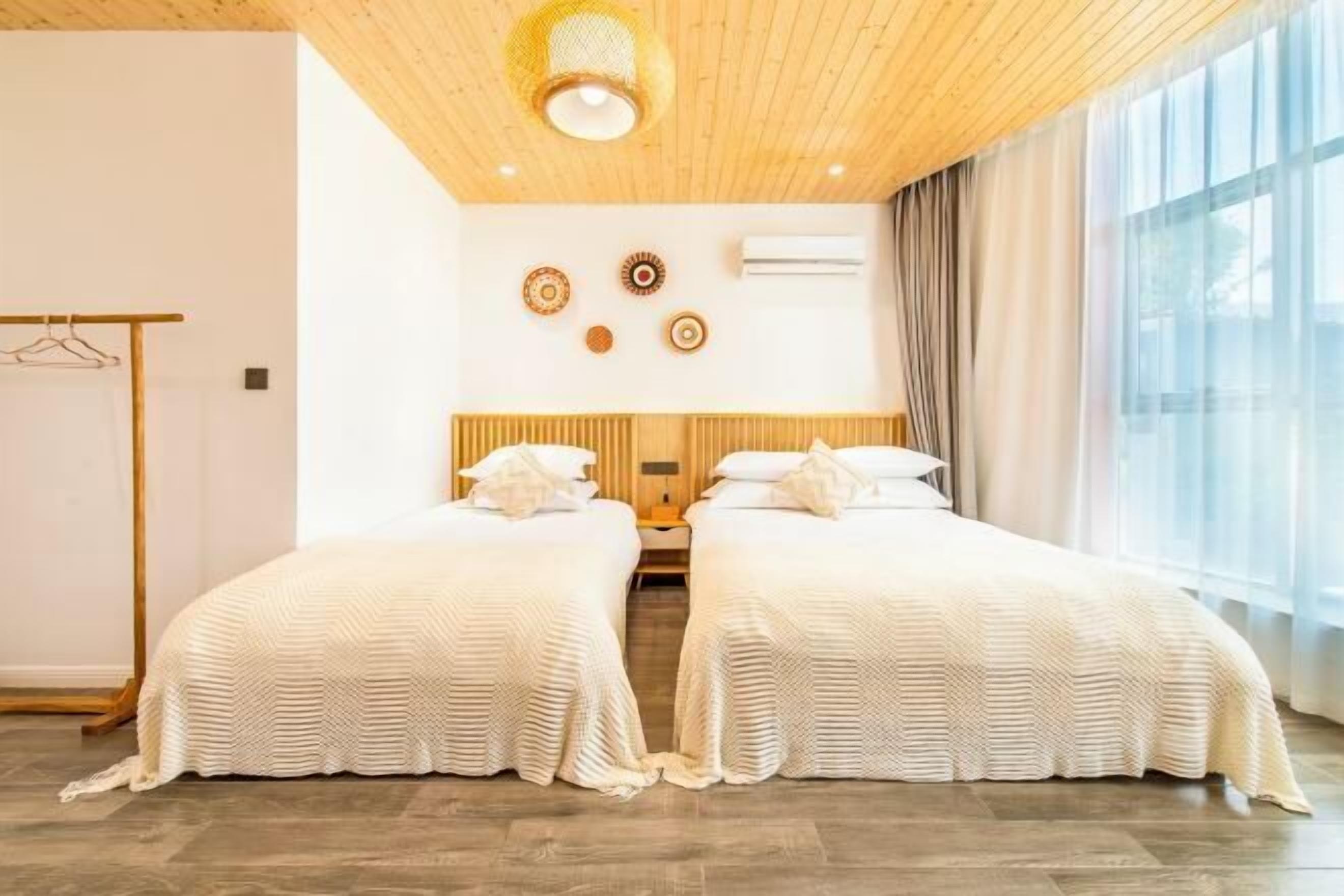 Une chambre d’hôtel avec deux lits, un plafond en bois et une grande fenêtre avec des rideaux.