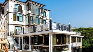 A multi-story building with a balcony on the upper level, large windows, and a covered area with tables and chairs. - Zhujiajian Haiyu Seaview BNB (Zhoushan)