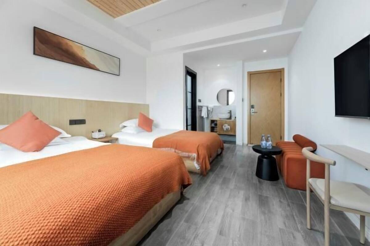 Ein Hotelzimmer mit zwei Betten, einem Sofa, einem kleinen Tisch und einem Fernseher.