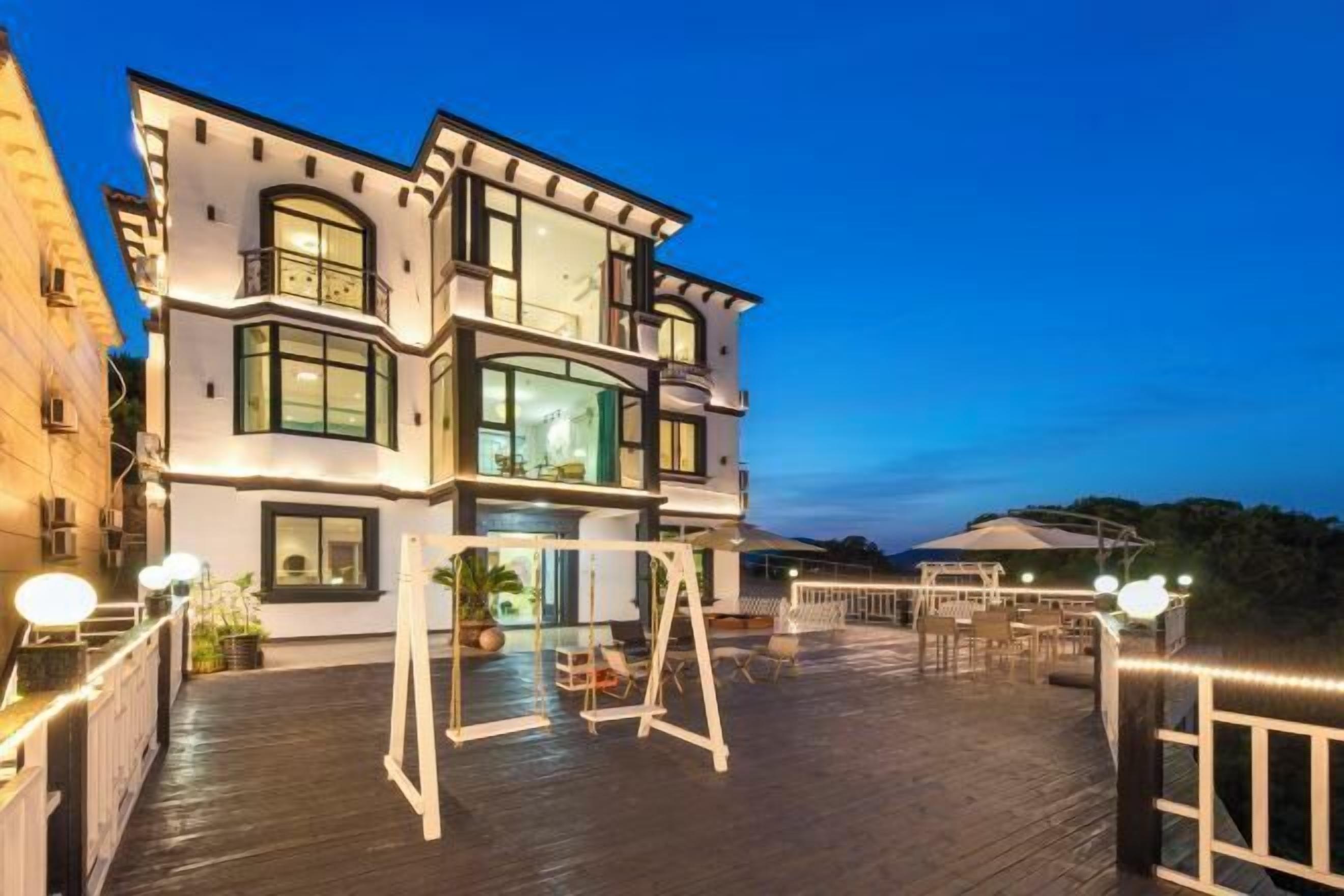 A modern multi-story building with a balcony area featuring outdoor seating and a swing set.