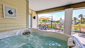 Een hottub met uitzicht op een patio, een inlijsting met een foto aan de muur en een heldere lucht.