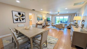 A modern living room with a dining area, a TV, and a large window with a view.