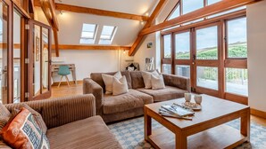 A spacious loft-style living room with a large window overlooking a scenic landscape.