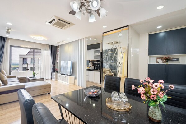 A modern living room with a black dining table, a sofa, and a large mirror.