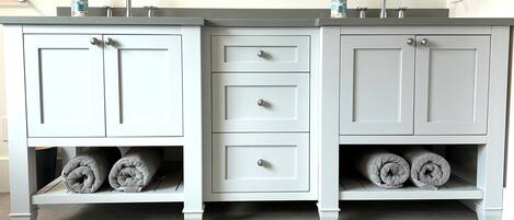 A bathroom with a white vanity, two sinks, and three drawers.