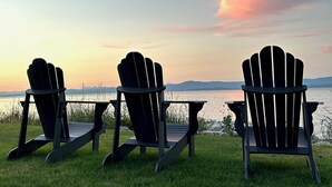 Three Adirondack chairs facing a body of water with a sunset sky. - NEW "Seabreeze B&B" on walkout beach in beautiful Qualicum Beach (Qualicum Beach)