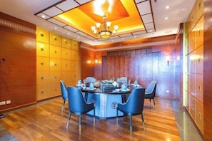 A modern hotel room with a round dining table, blue chairs, and a chandelier. - Nanshan Hotel (Sanya)