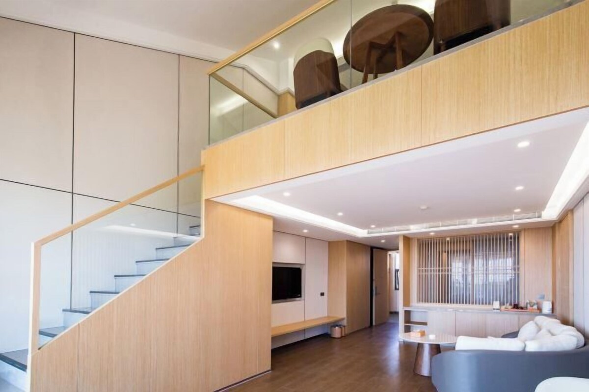 A modern interior with a staircase, a seating area, and a television.