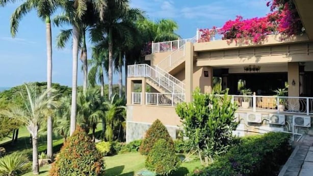 A two-story building with a balcony, surrounded by lush greenery and palm trees. - Nanshan Hotel (Sanya)