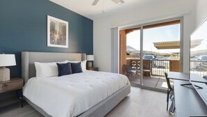 Habitación de hotel moderna con una cama grande, un escritorio y un balcón con vista al estacionamiento.