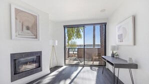 A modern living room with a fireplace, a large window, and a balcony with a view of the city. - Landing | Incredible Studio, Gym, Pool (Tempe)