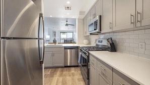A modern kitchen with stainless steel appliances, grey cabinetry, and a tiled backsplash. - Landing | Incredible Studio, Gym, Pool (Tempe)