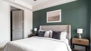 A bedroom with a bed, two bedside tables, and a nightstand. - Landing | Stylish 2BD, Courtyard, Gym (Houston)