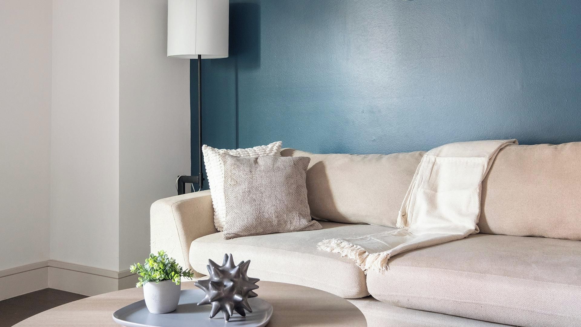 Un salon moderne avec un canapé beige, une table basse ronde, une plante en pot et un objet décoratif en forme d’étoile.