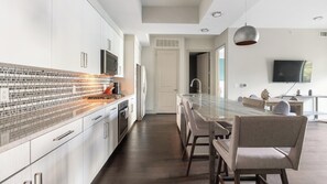 A modern kitchen with a tiled backsplash, stainless steel appliances, and a central island with bar stools.