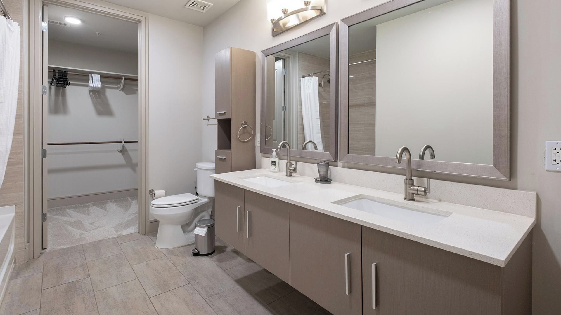 A modern bathroom with a toilet, bidet, sink, and mirror.