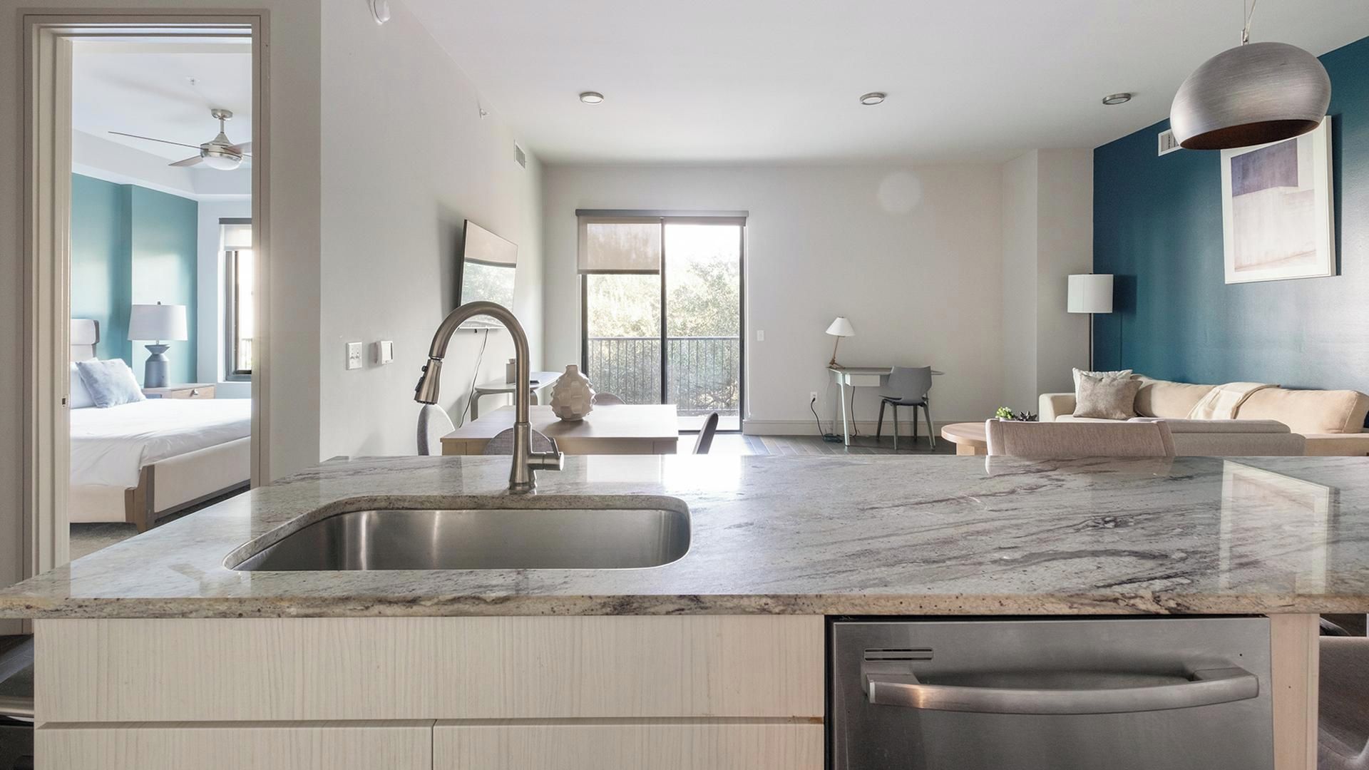 Una cocina moderna con lavavajillas incorporado, un lavaplatos grande y una zona de comedor con mesa y sillas.