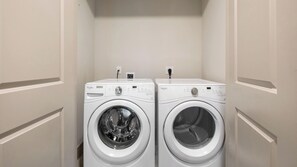 A laundry room with two front-loading Whirlpool washers and a small shelf above them. - Landing | Beautiful 2BD, Pool, Gym (Houston)