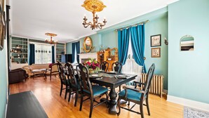 A dining room with a wooden table set for four, surrounded by chairs, a chandelier, and a blue curtain. - Downtown St. Charles: Walk to Bars & Restaurants (St. Charles)