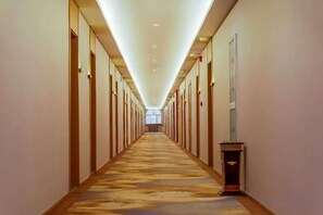 A hotel corridor with a carpeted floor, doors on both sides, and a light fixture on the ceiling. - YunLong HOTEL (Ongniud Banner)