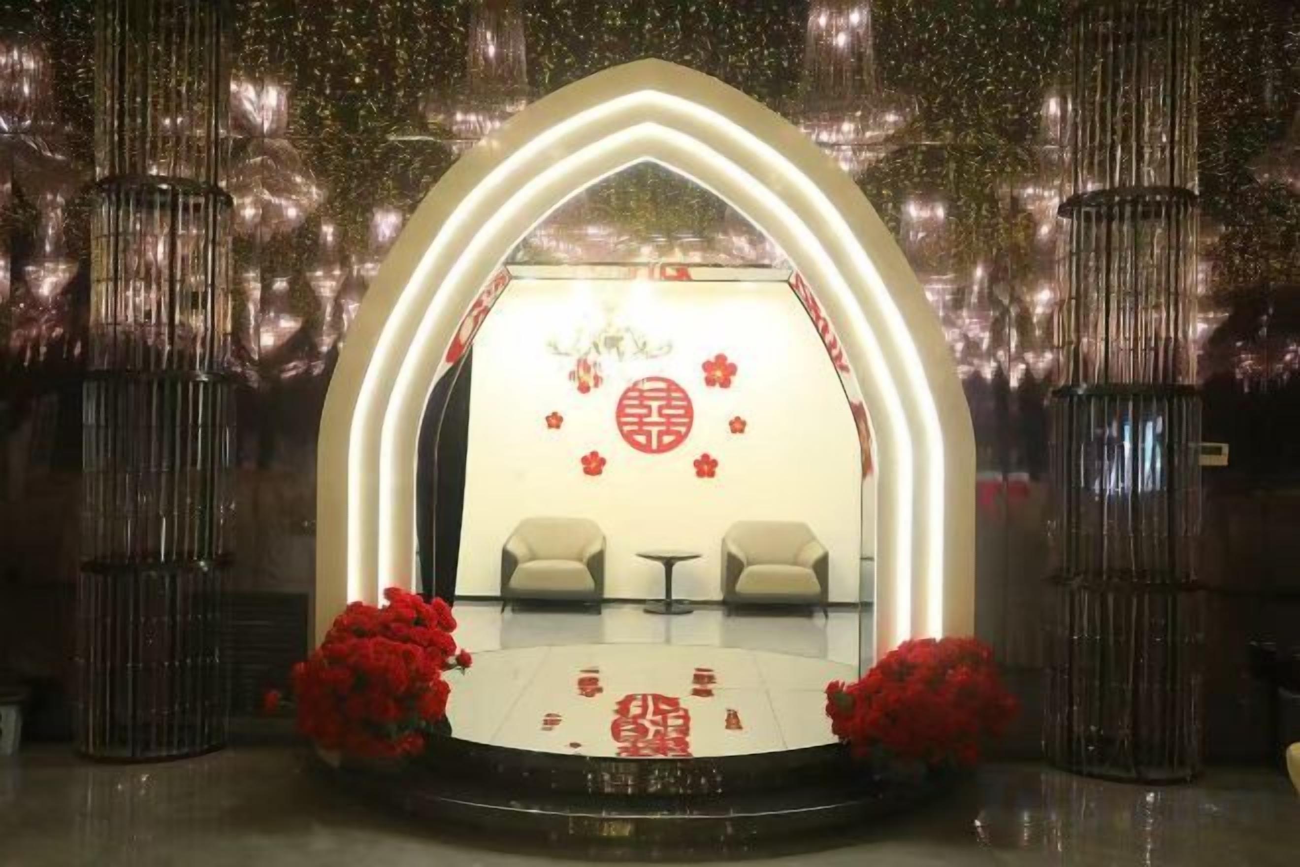 A stage with a circular emblem, two chairs, and red flowers.