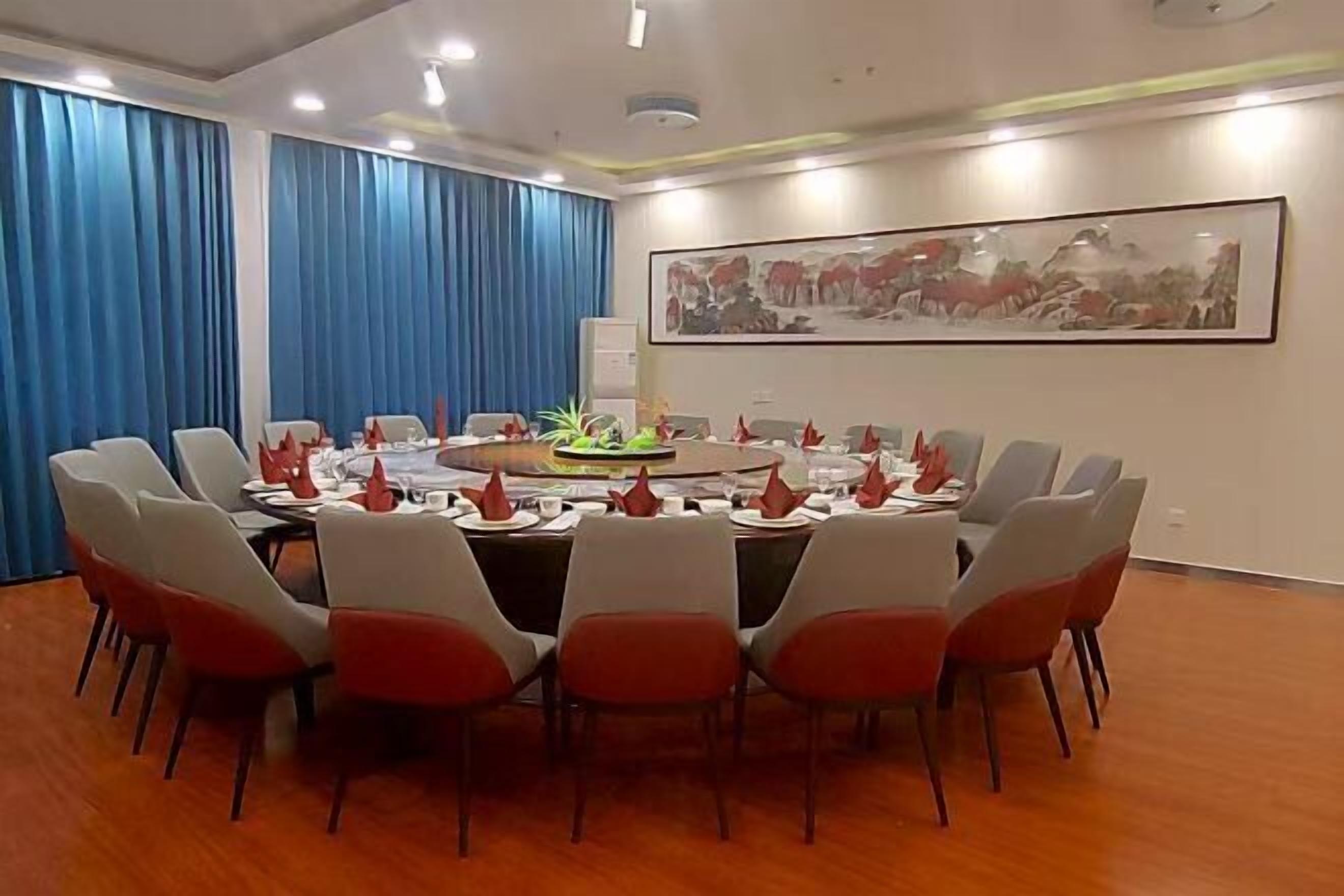 A conference room with a round table, chairs, and a painting on the wall.