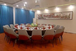 A conference room with a round table, chairs, and a painting on the wall. - YunLong HOTEL (Ongniud Banner)