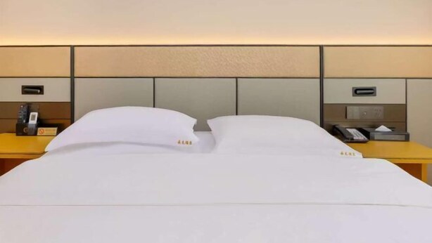A hotel room with a bed, bedside tables, and a headboard. - YunLong HOTEL (Ongniud Banner)