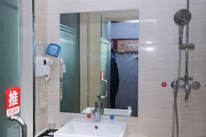 A bathroom with a sink, mirror, and shower. - YunLong HOTEL (Ongniud Banner)
