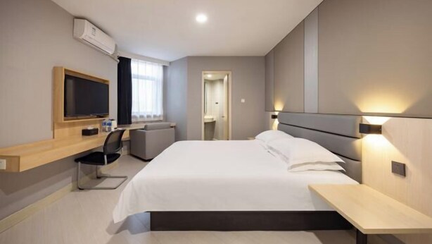 A modern hotel room with a bed, bedside table, TV, and a desk with a chair. - Jinzhou Star Hotel (Jinzhou Luoyang Road) (Jinzhou)