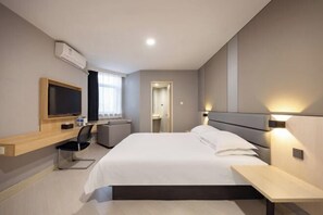 A modern hotel room with a bed, bedside table, TV, and a desk with a chair. - Jinzhou Star Hotel (Jinzhou Luoyang Road) (Jinzhou)