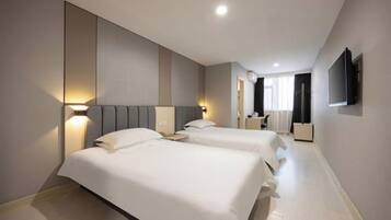 Habitación de hotel con dos camas, una televisión montada en la pared y una mesita de noche con lámpara.