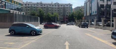 Una calle con automóviles estacionados y edificios al fondo.