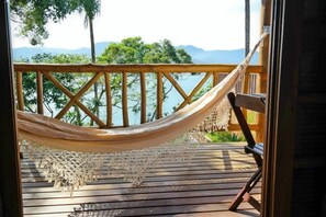 A hammock on a wooden deck with a view of a lake and mountains. - Gidu House (Ilhabela)