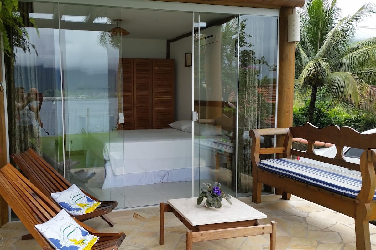 Una habitación con cama, un banco de madera y una mesita con una planta.