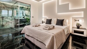 A modern bedroom with a large bed, a glass shower enclosure, and a marble floor. - Hollywood 3 Bedroom Villa with private pool (Ampelokipoi)