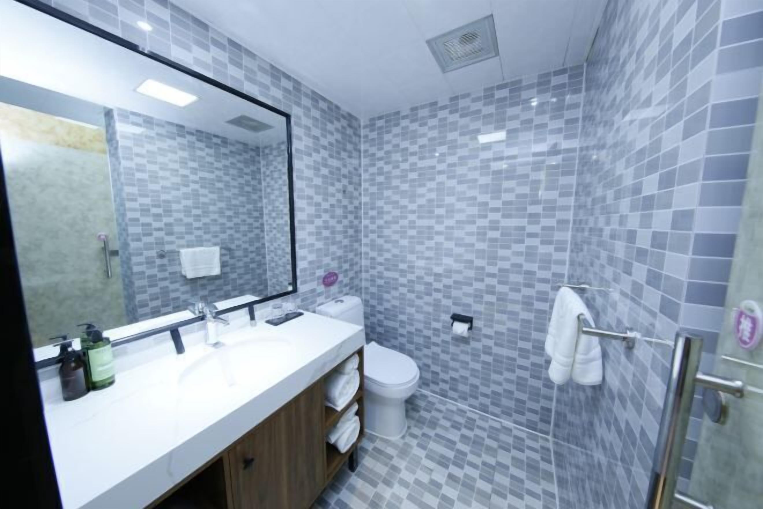A bathroom with a tiled wall, a sink, a toilet, and a mirror.
