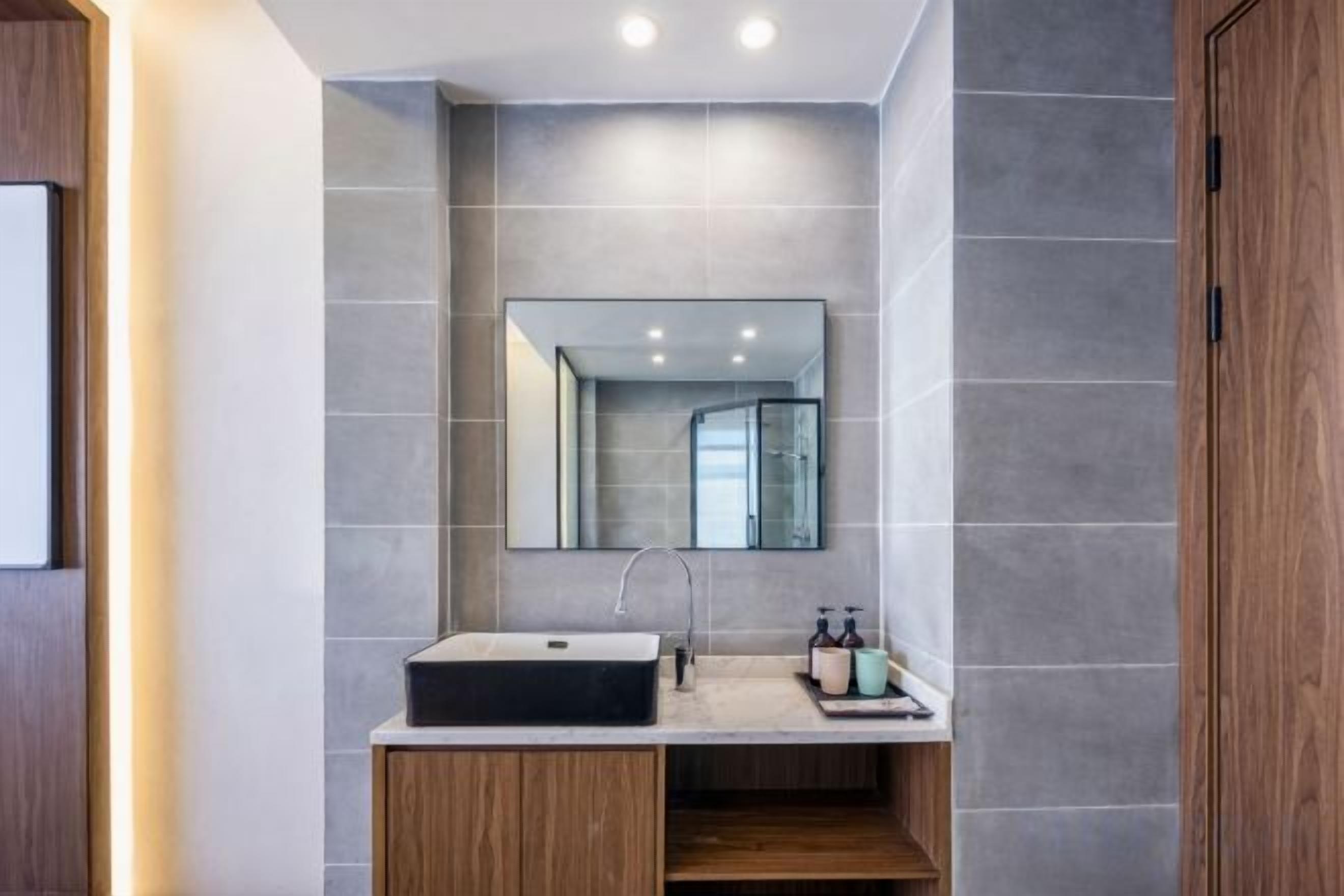 Un baño moderno con un lavamanos rectangular, un espejo encima y un gabinete de madera debajo.