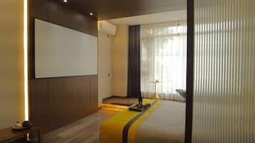 Een moderne hotelkamer met een groot bed, een flatscreen televisie en een zithoek met een tafel en stoelen.