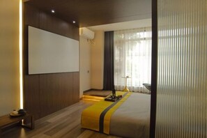 A modern hotel room with a large bed, a flat-screen TV, and a seating area with a table and chairs. - Yinan Inn (Dujiangyan)