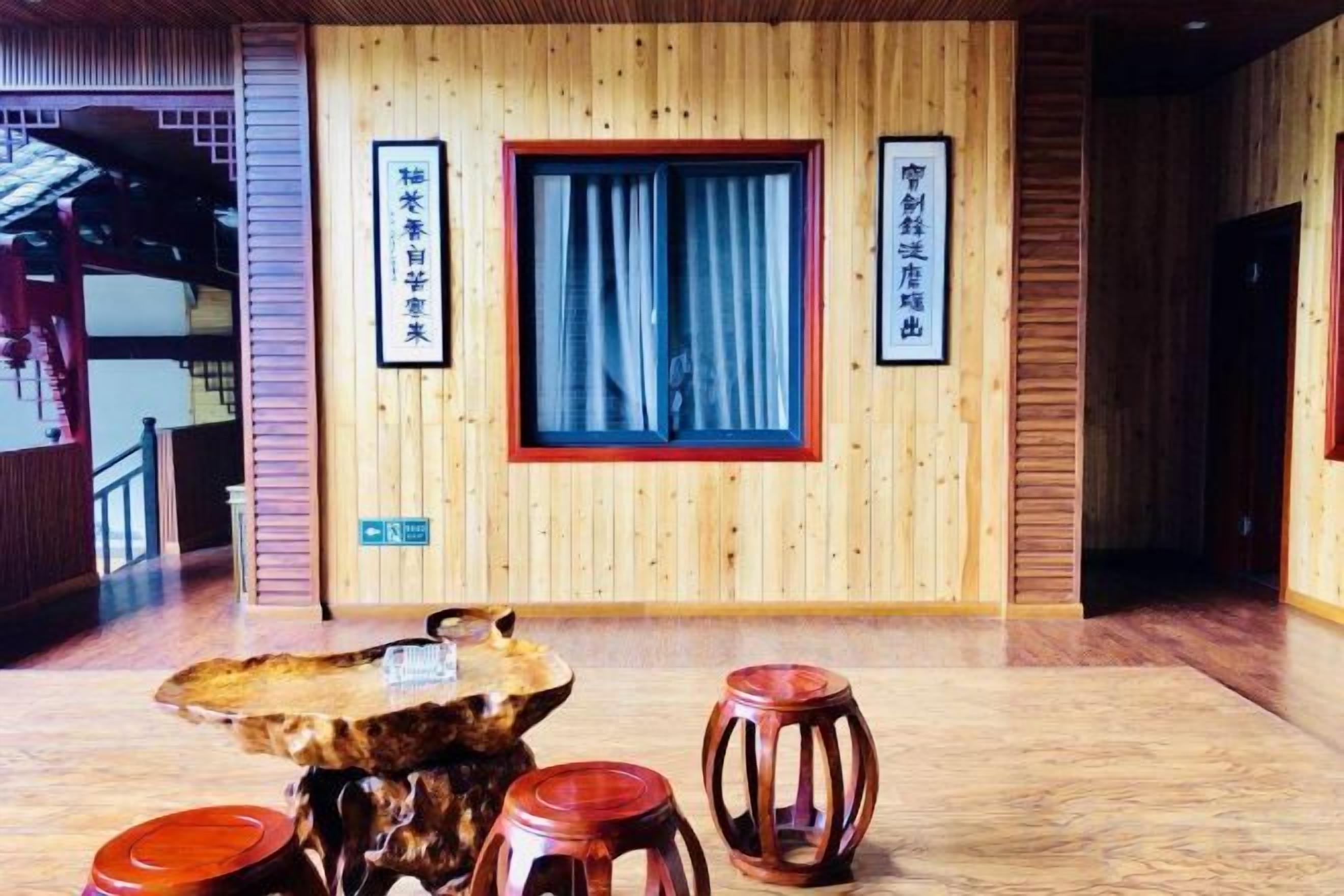 Interior em madeira com mesa, banquinhos e janela com cortinas.