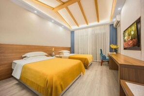 A hotel room with two beds, a desk, a chair, and a large window with blinds. - Yinan Inn (Dujiangyan)