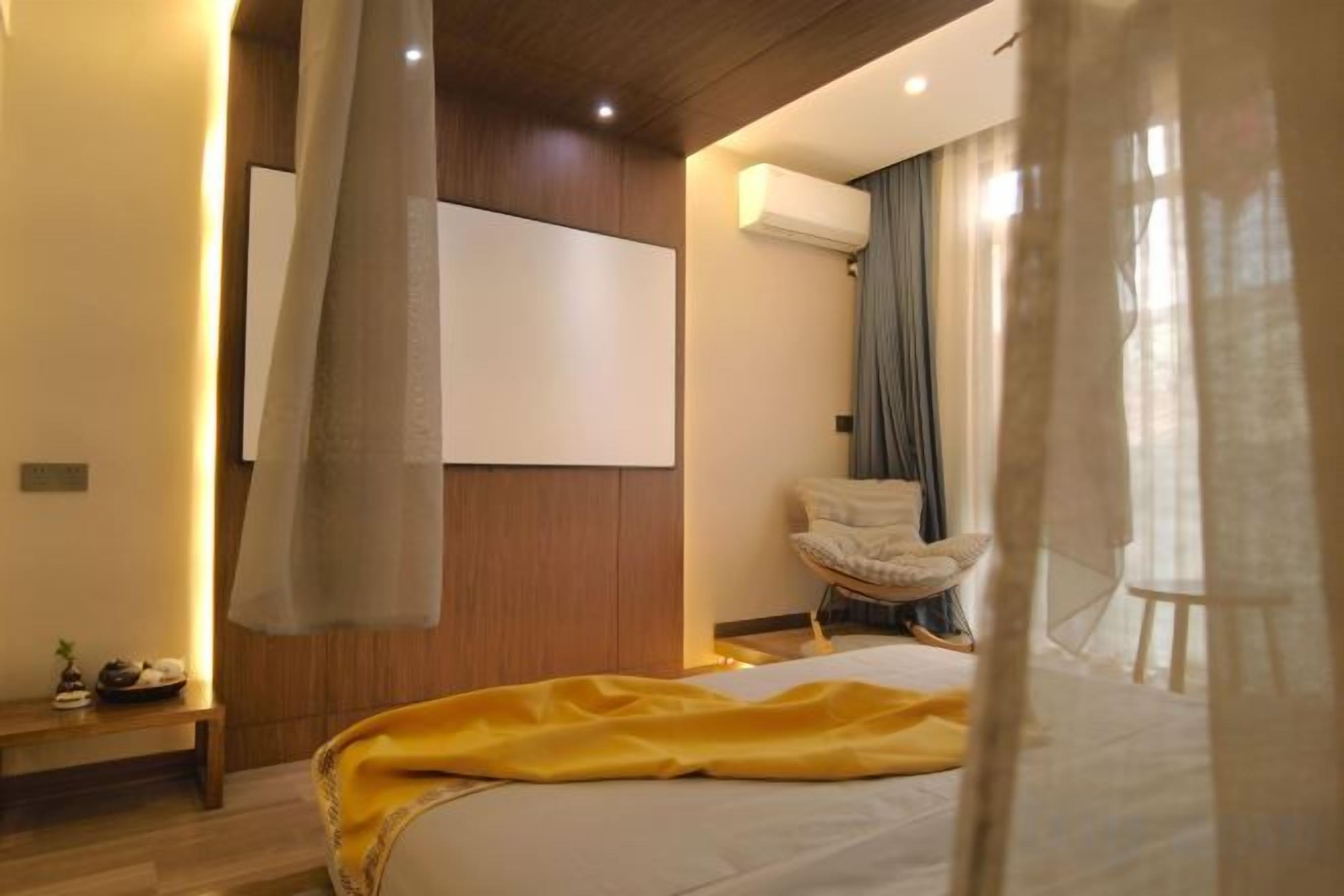 Quarto com cama, cadeira, mesa de cabeceira e um espelho grande.