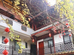 Edifici tradicional amb un balcó, fanals vermells i façana blanca.