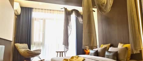 A modern room with a sofa, a chair, and a bed with a canopy.
