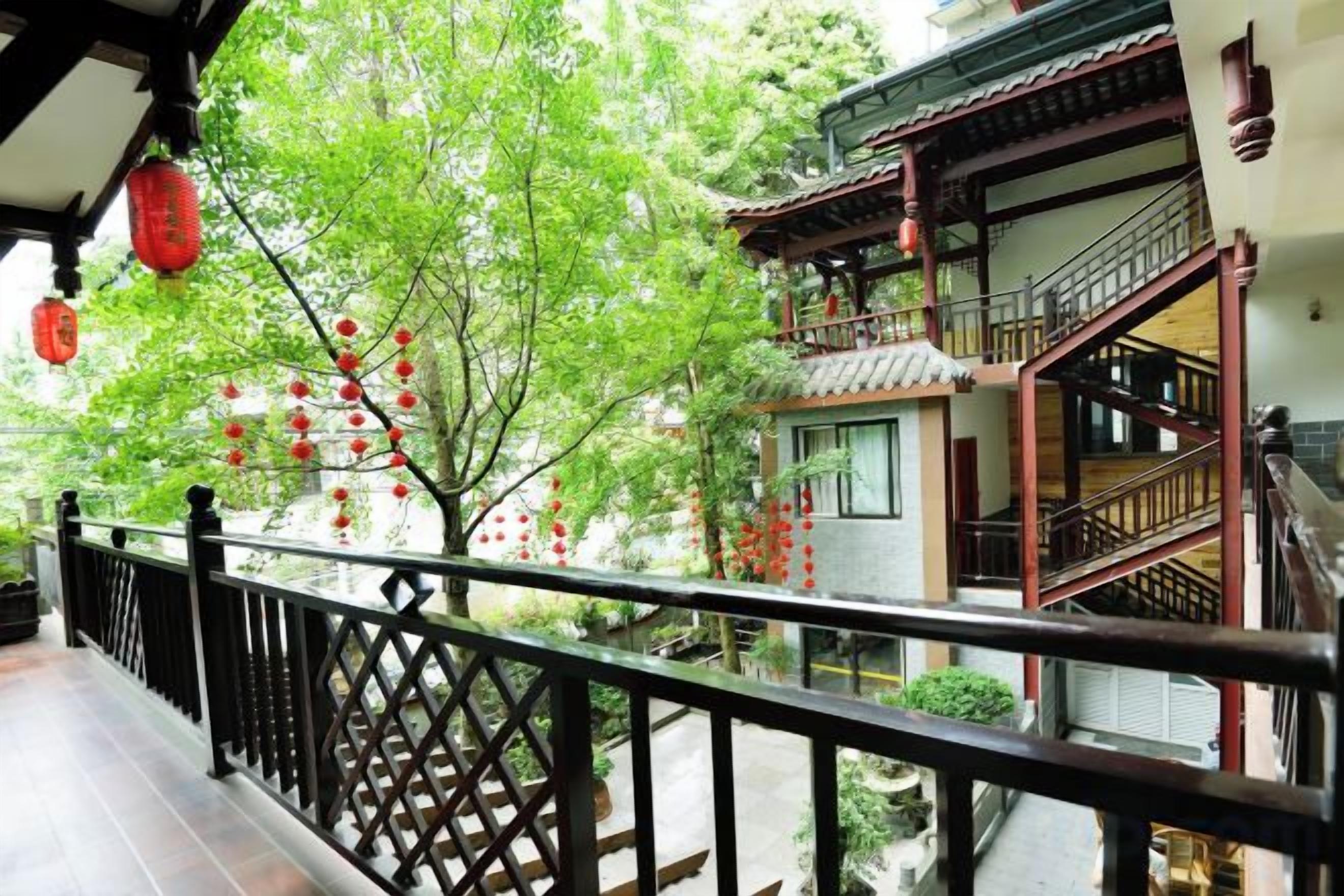 Un edificio tradizionale con un balcone in legno, una scala e un albero addobbato con decorazioni rosse.