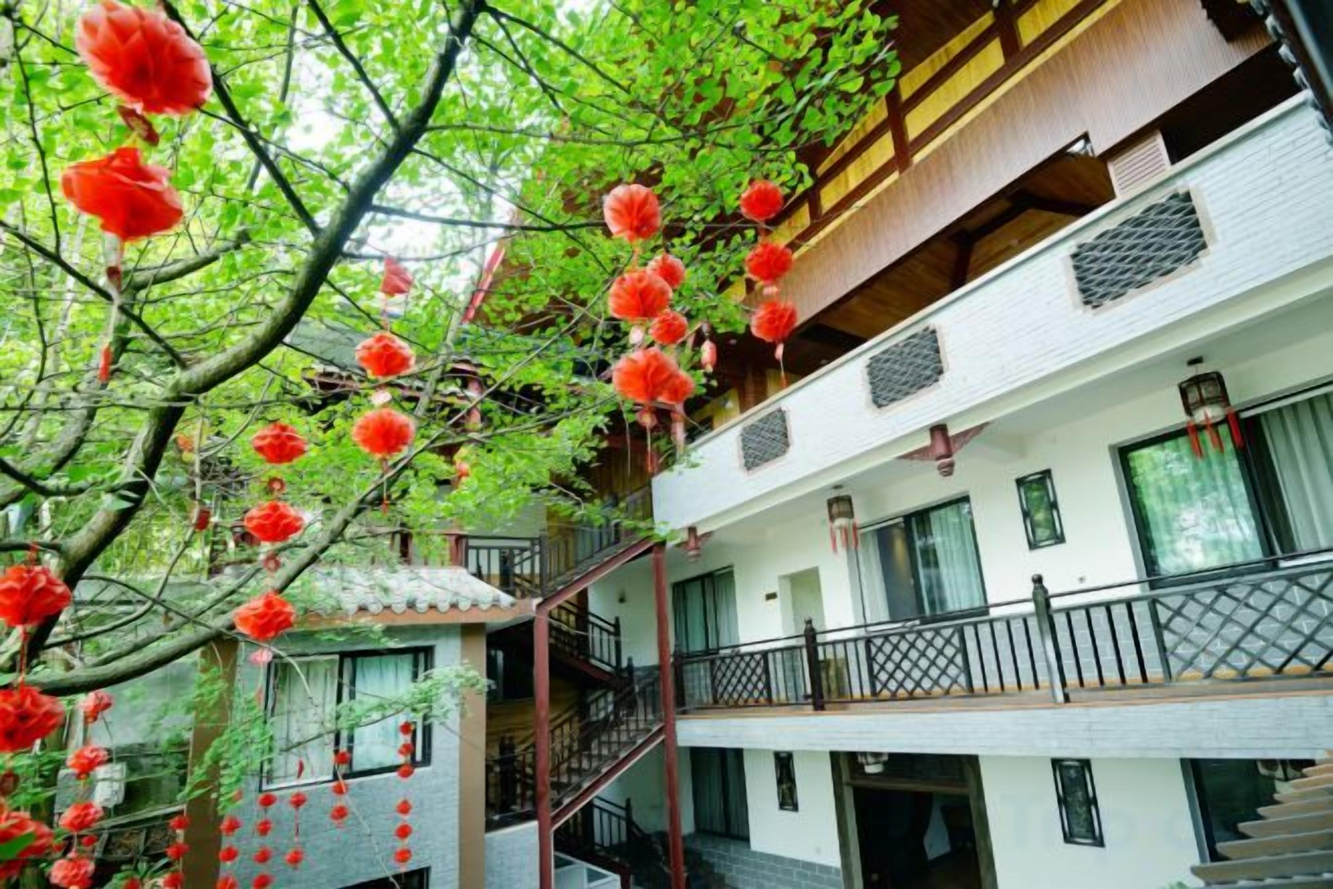A multi-story building with balconies, staircases, and a tree with hanging red decorations.