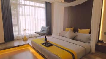 A modern hotel room with a large bed, a chair, and a bedside table.