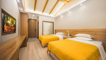 A hotel room with two beds, a wooden headboard, a desk, and a painting on the wall.