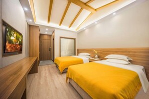 Habitación de hotel con dos camas, cabecero de madera, escritorio y un cuadro en la pared.
